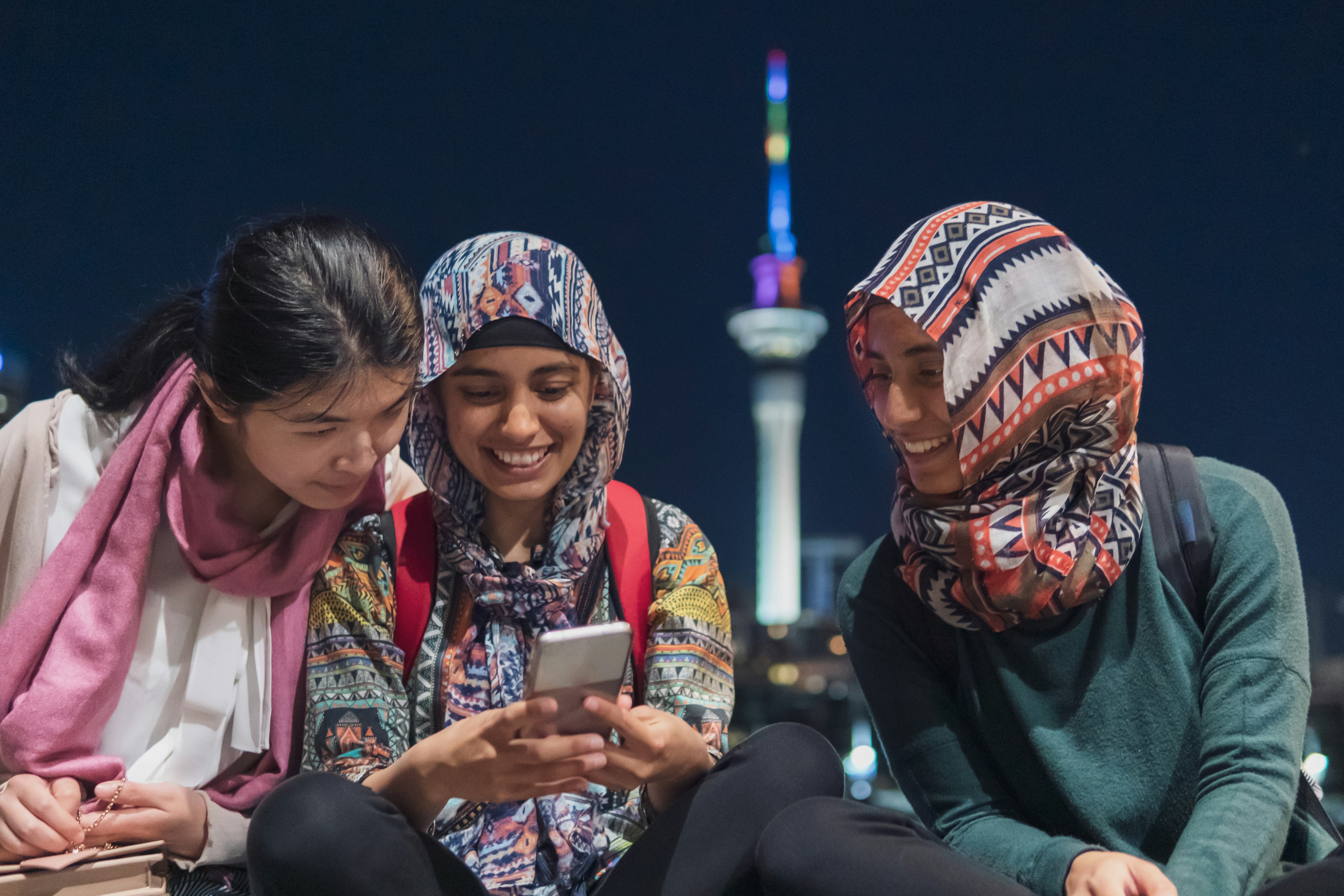 Gen Z Muslim women chatting in front of the Auckland Sky Tower