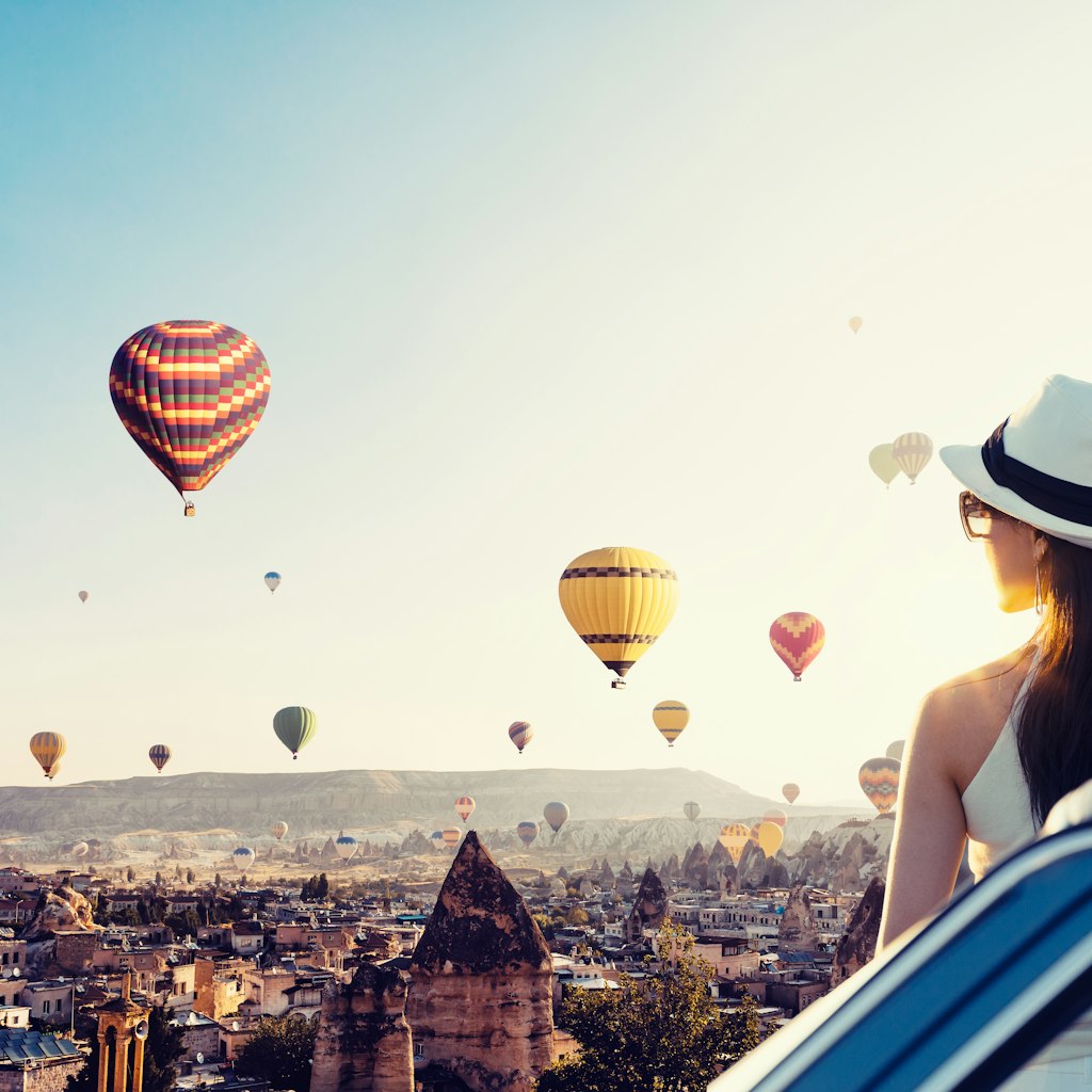 A woman watching balloons in Cappadocia by a car
