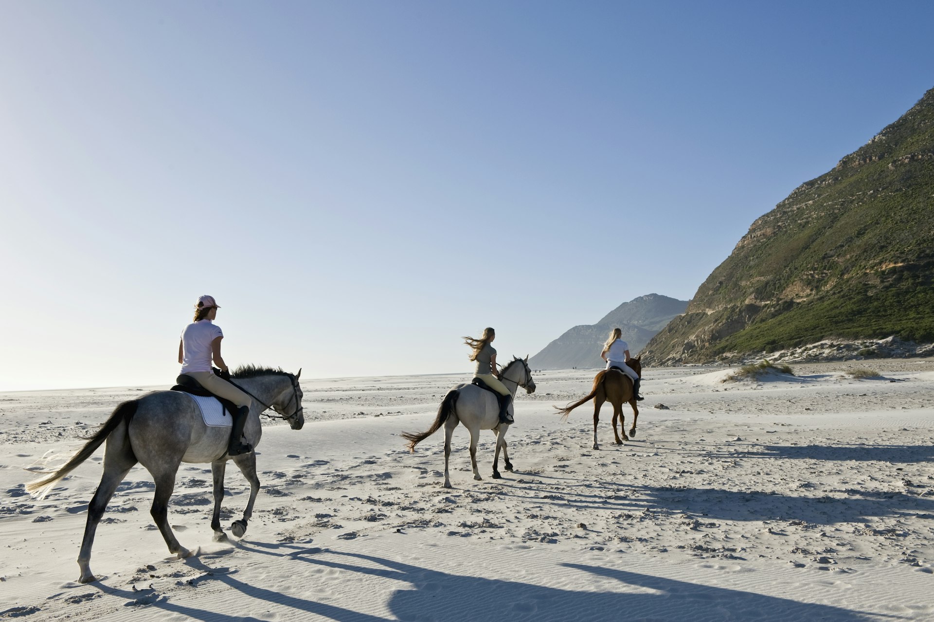 Women riding horses along Noordhoek Beach, South Africa
