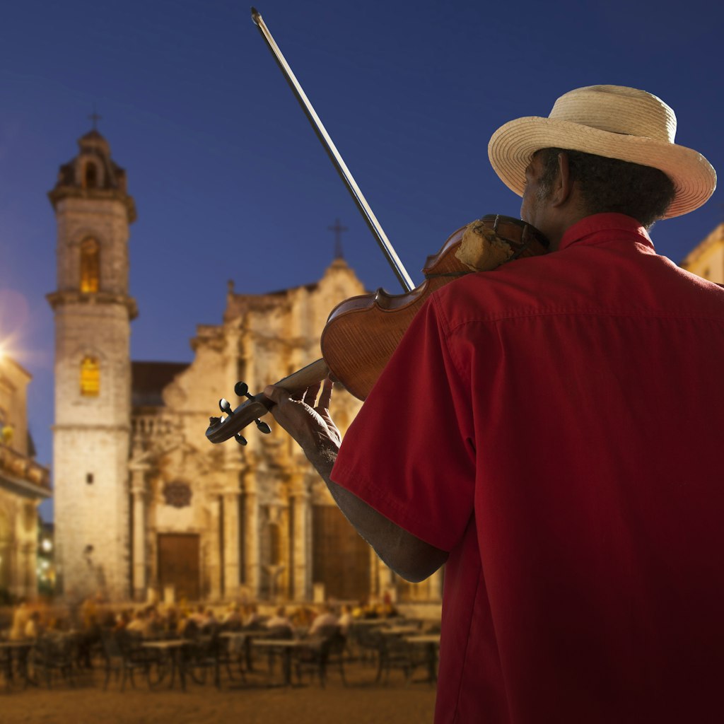 Senior man playing violin at night in Plaza de la Catedral, Havana, Cuba