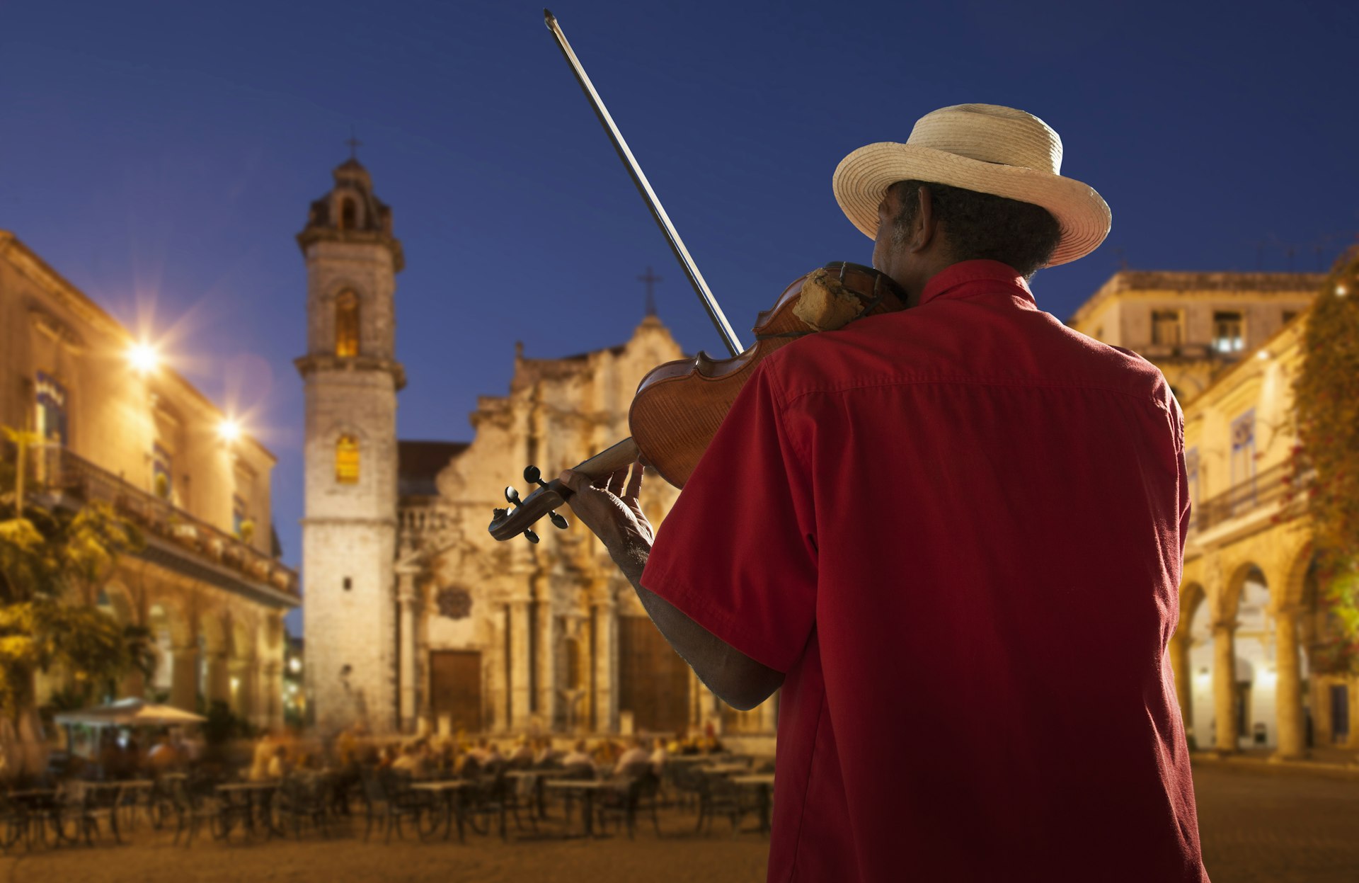 Senior man playing the violin at night in Plaza de la Catedral, Havana, Cuba