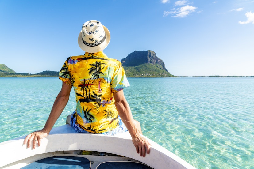 Man in a tropical shirt on a boat in front of Le Morne Brabant, Mauritius