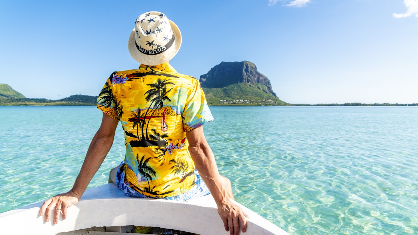 Man in a tropical shirt on a boat in front of Le Morne Brabant, Mauritius