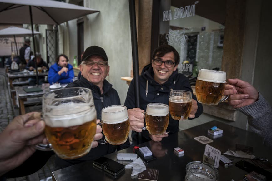 Men raise their beer glasses in a toast at an outdoor pub in Prague