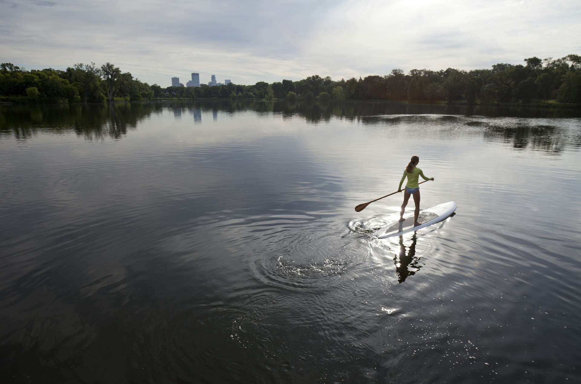 A woman stand-up paddleboarding on a Minneapolis lake