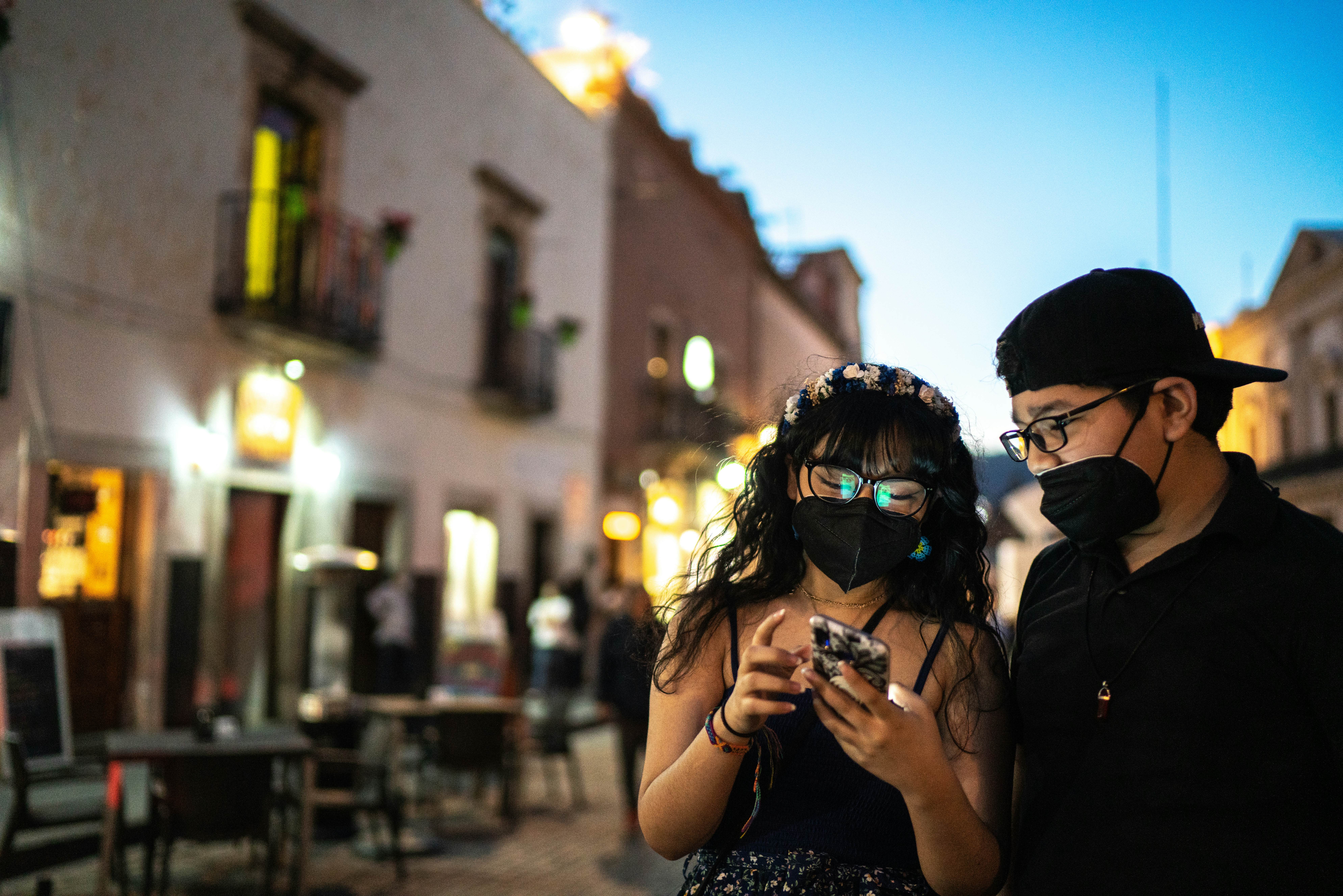 Man and Woman wearing masks looking at phone