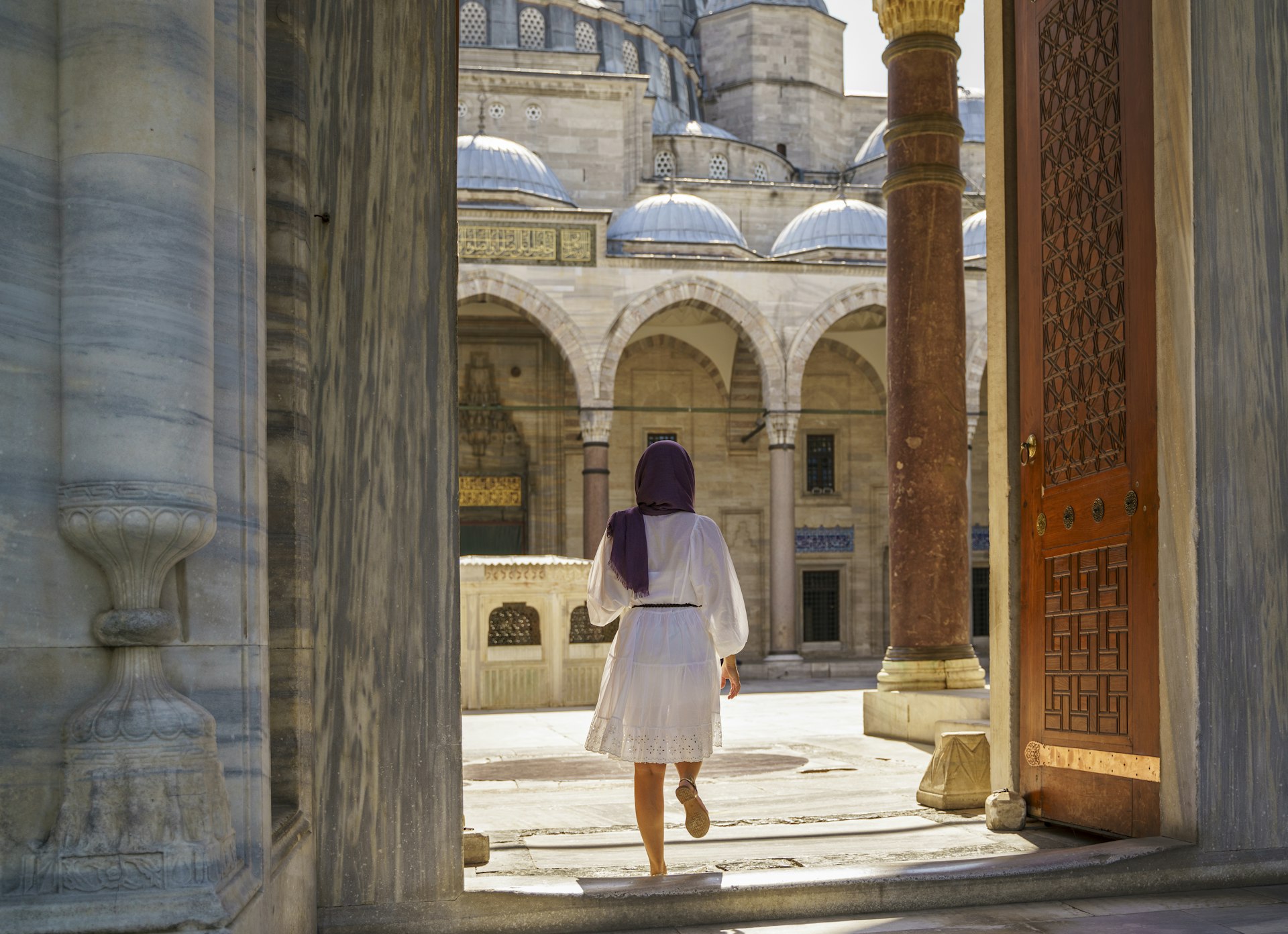 Young beautiful muslim woman posing in courtyard of Suleymaniye mosque in Istanbul, Turkey