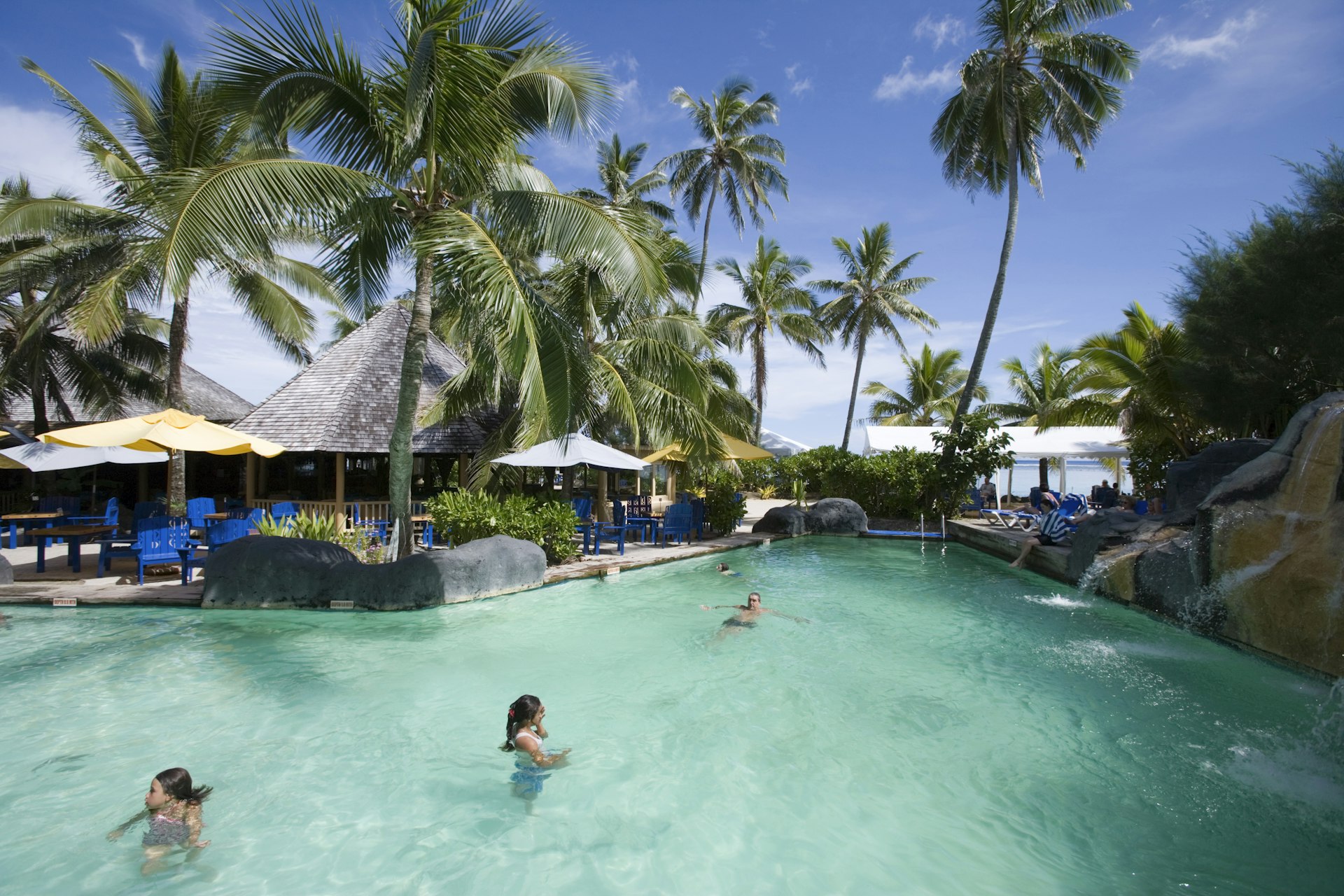 People swimming in the pool at Rarotongan Beach Resort on a clear day