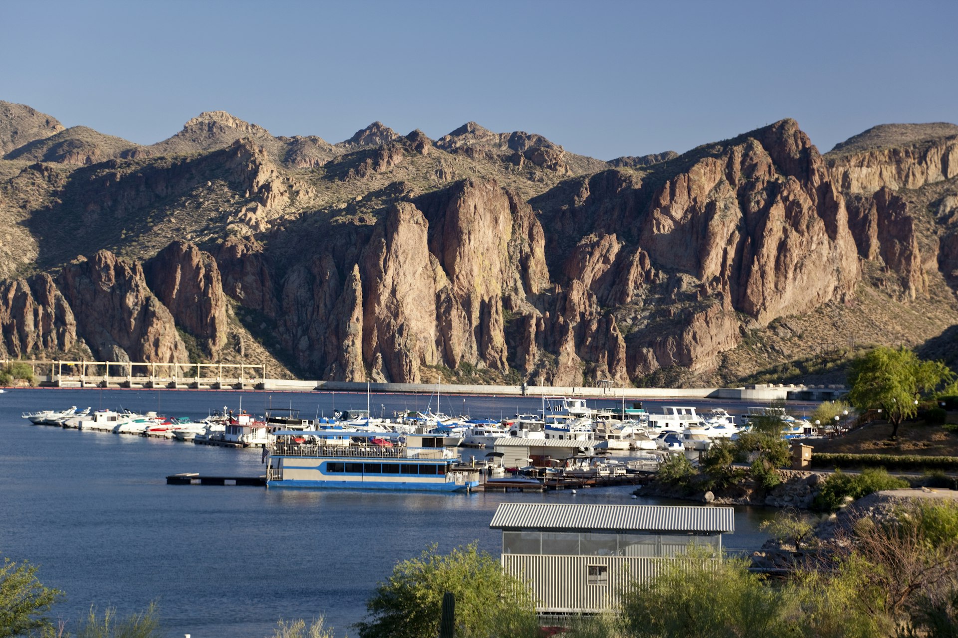 Boats docked at the marina of Saguaro Lake with desert cliffs in the distance