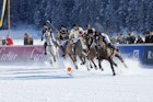 St. Moritz, Switzerland - January 27, 2013: Polo Players chase after the ball at the St. Moritz Polo World Cup on Snow while spectators are watching. The St. Moritz Polo World Cup on Snow is the worlds most prestigious winter polo tournament. Four high-goal teams with handicaps between 15 and 18 goals battle for the coveted Trophy on the frozen surface of Lake St. Moritz.