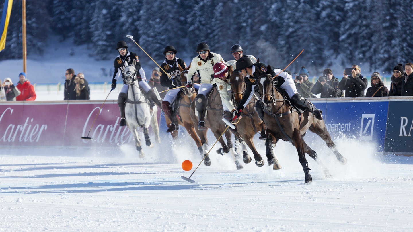 St. Moritz, Switzerland - January 27, 2013: Polo Players chase after the ball at the St. Moritz Polo World Cup on Snow while spectators are watching. The St. Moritz Polo World Cup on Snow is the worlds most prestigious winter polo tournament. Four high-goal teams with handicaps between 15 and 18 goals battle for the coveted Trophy on the frozen surface of Lake St. Moritz.
