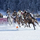 St. Moritz, Switzerland - January 27, 2013: Polo Players chase after the ball at the St. Moritz Polo World Cup on Snow while spectators are watching. The St. Moritz Polo World Cup on Snow is the worlds most prestigious winter polo tournament. Four high-goal teams with handicaps between 15 and 18 goals battle for the coveted Trophy on the frozen surface of Lake St. Moritz.