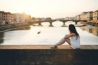 A woman watches the sunset along the river in Florence