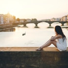 A woman watches the sunset along the river in Florence