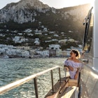 A woman in sunglasses on a boat approaching Capri