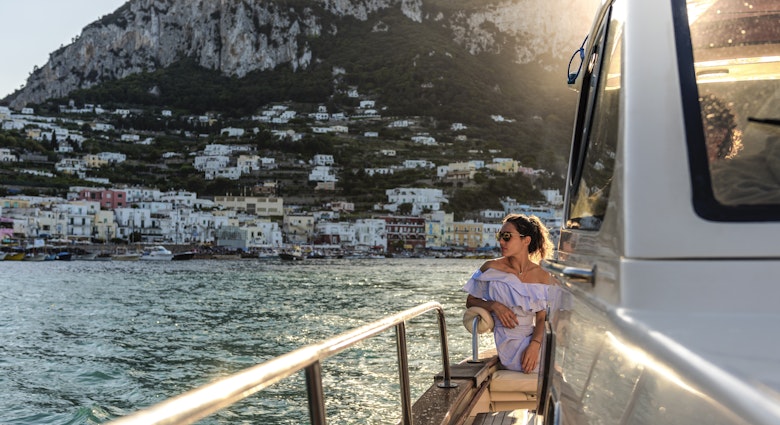A woman in sunglasses on a boat approaching Capri