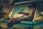 Driver in cowboy outfit in a classic car in Texas