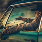 Driver in cowboy outfit in a classic car in Texas