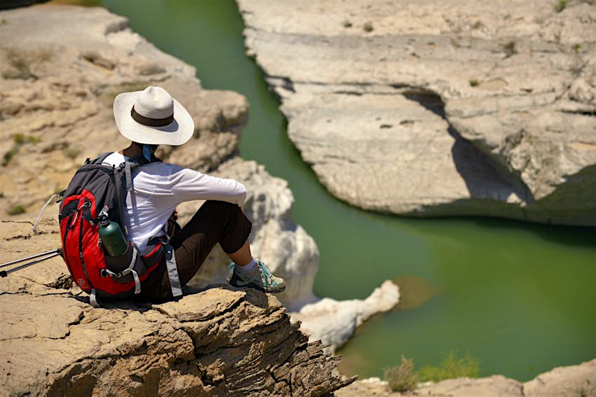Los visitantes de Omán pueden explorar impresionantes paisajes desérticos y costeros. Una mujer mirando un paisaje rocoso en Omán