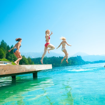Teenage girls jumping from pier in the lake. Bled. Slovenia