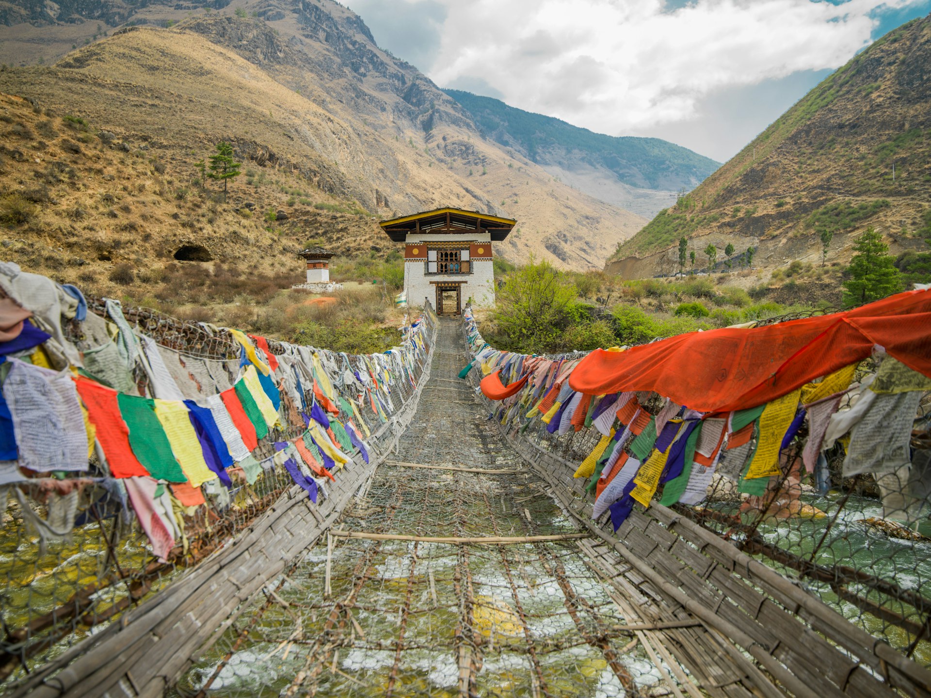 Tachog Lhakhang Iron Chain Bridge with colourful prayer flags on each side of bridge, Bhutan