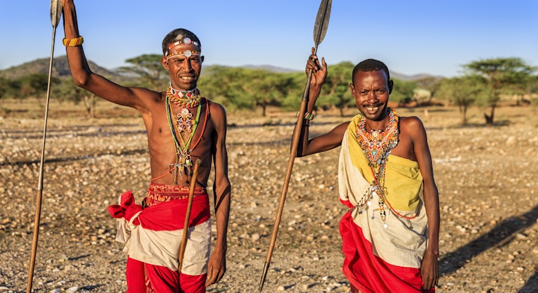 African warriors from Samburu tribe standing on savanna and holding a spears, central Kenya. Samburu tribe is one of the biggest tribes of north-central Kenya, and they are related to the Maasai.