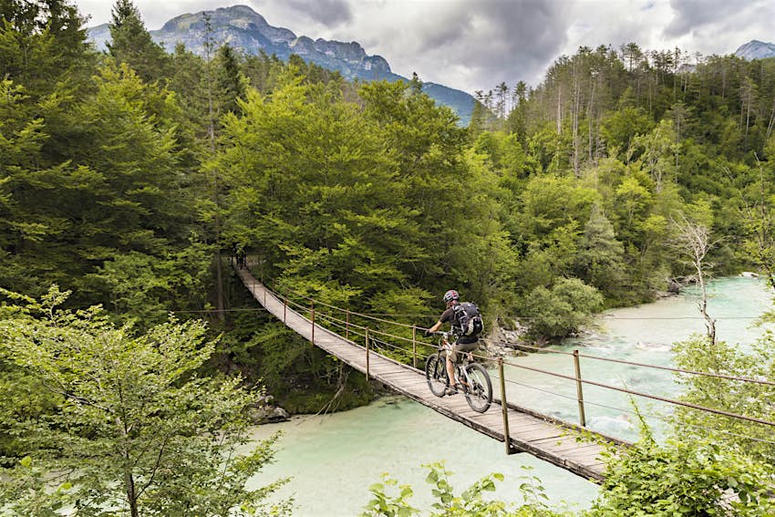Male mountainbiker is crossing a suspension bridge in Slovenia.