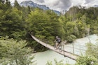 Male mountain biker crossing a suspension bridge over the Soča River in the Julian Alps of northern Slovenia.
