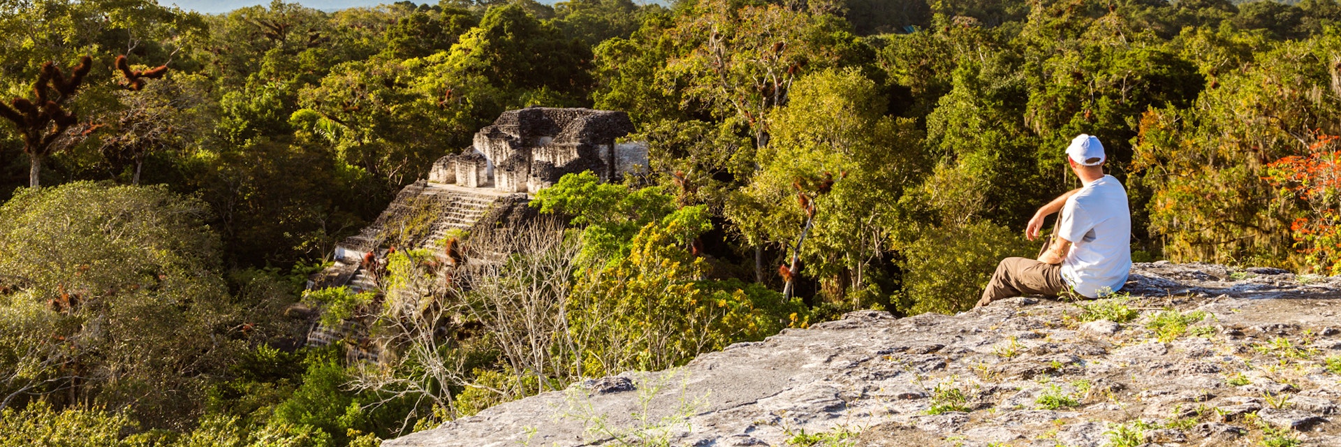 Tourist looking at old mayan ruins from high lookout (Temple IV and temple of the Lost World), Tikal National Park, Peten, Guatemala