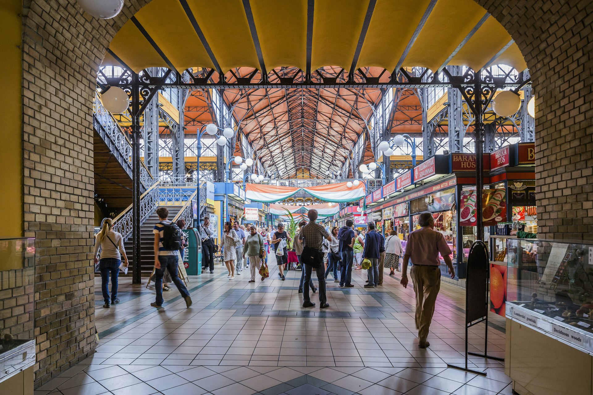 A busy indoor market place with lots of people walking through