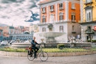 Naples, Italy - October 17, 2018: Adult Caucasian Man Tourist Riding On Bicycle Near Fontana del Carciofo.