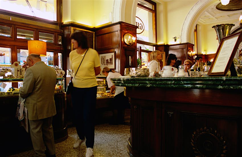 A woman walks past a patron sipping coffee at Caffè Gilli in Florence.