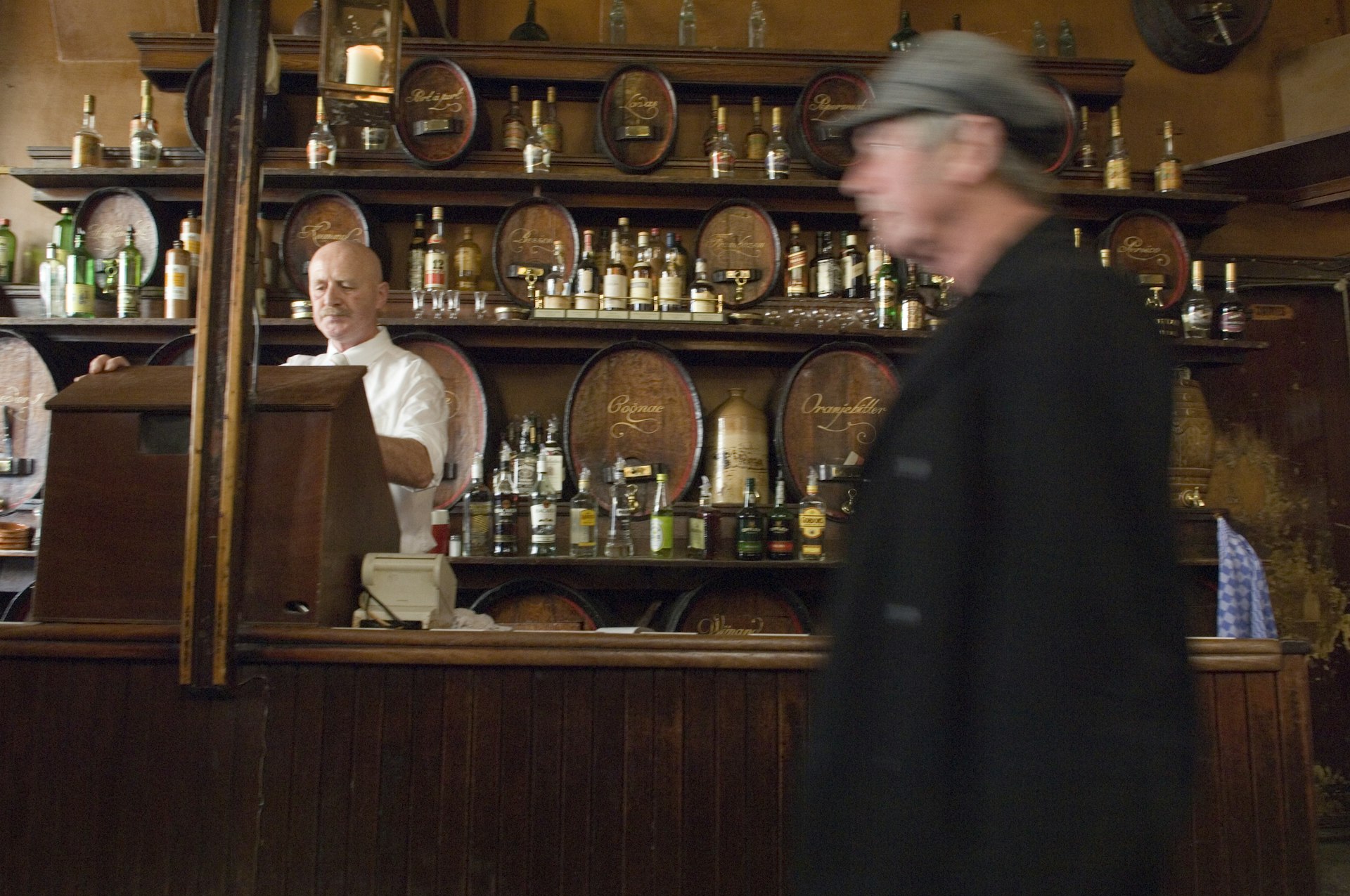 A patron walks by a bartender behind the bar at historic Amsterdam bar Hoppe