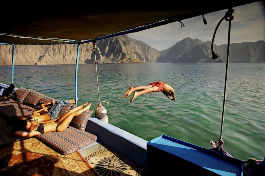 Man diving off tour boat cruising Musandam Coast in Oman