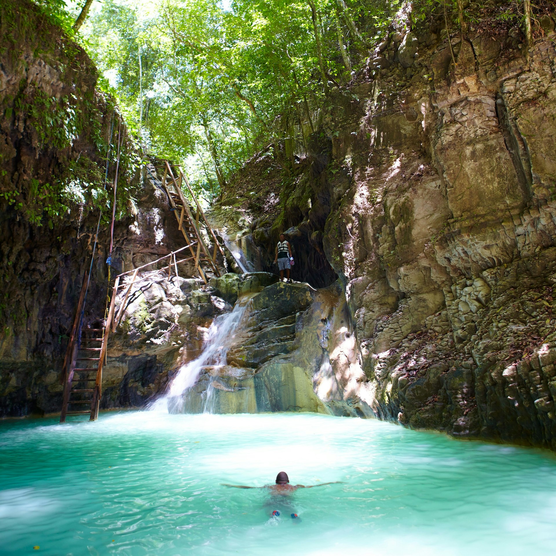 A man swimming in the bright blue waters of the pool by the Saltos de la Damajagua