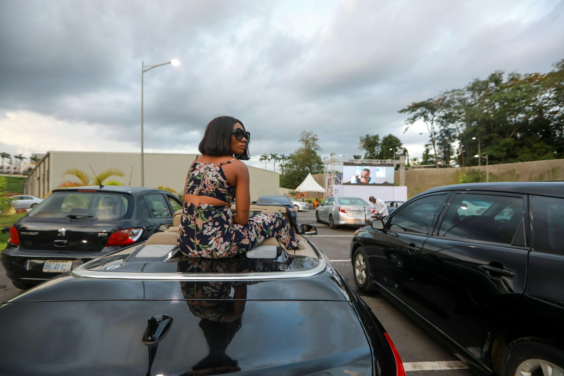 A woman sits on a car to watch Living in bondage movie at a drive-in cinema, following the relaxation of lockdown, amid the coronavirus disease (COVID-19) outbreak in Abuja, Nigeria May 20, 2020. Picture taken May 20, 2020. REUTERS/Afolabi Sotunde