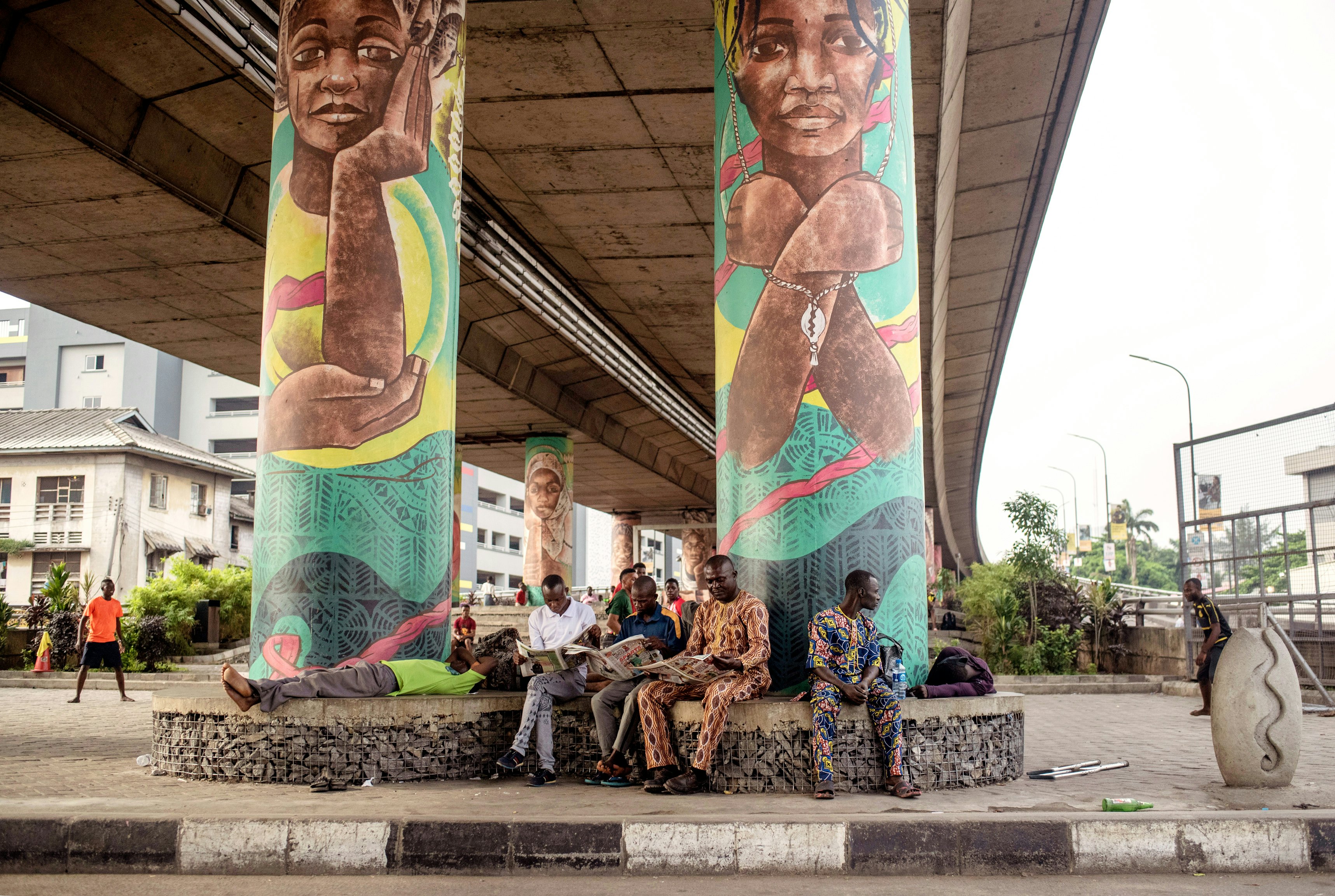 Men sit and read the morning papers under a bridge in Lagos.