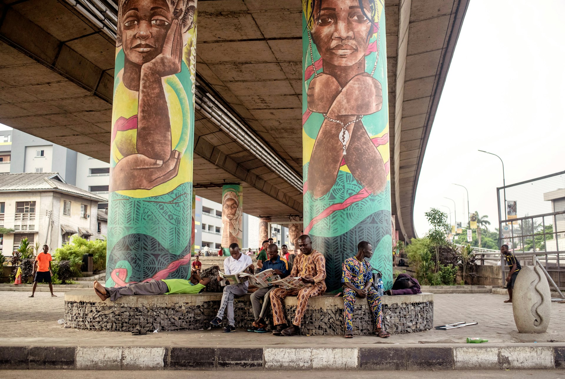 Men sit and read the morning papers under a bridge in Lagos.