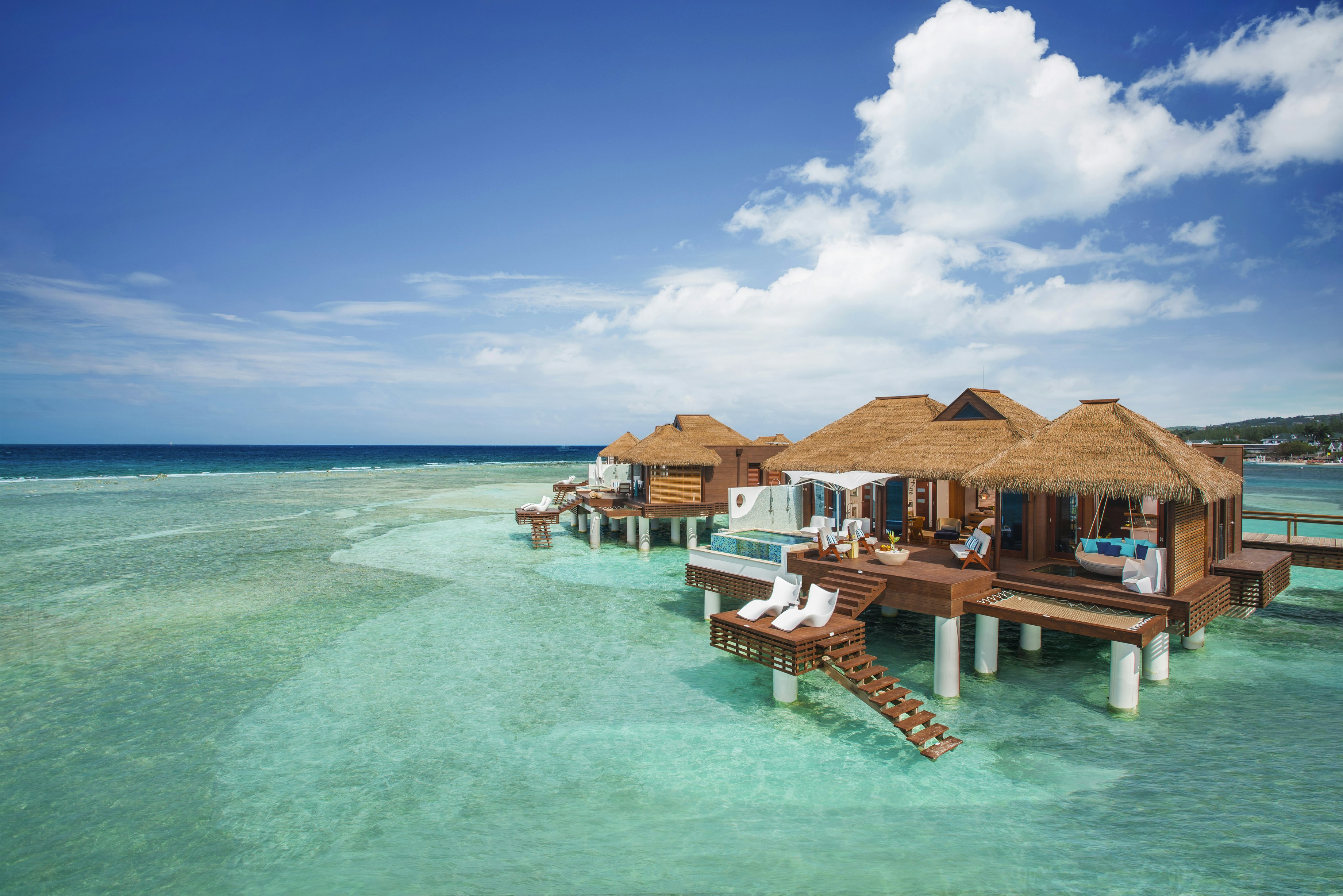 The clear, calm waters surround one of the overwater bungalows at Sandals Royal Caribbean