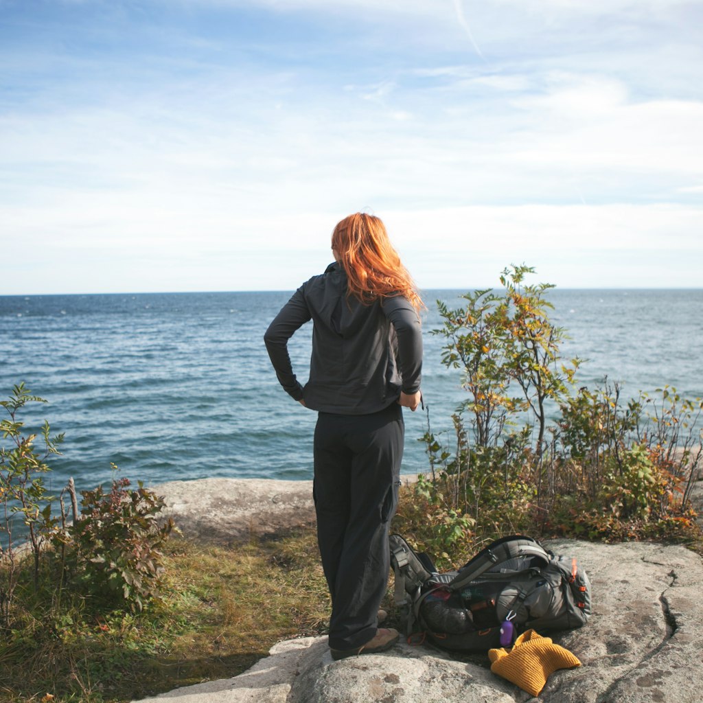 Redheaded woman standing on the rocky shores of Lake Superior in Northern Minnesota