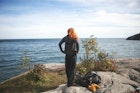 Redheaded woman standing on the rocky shores of Lake Superior in Northern Minnesota