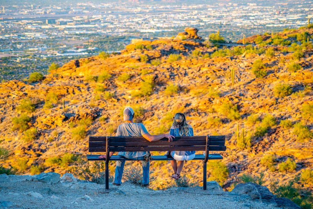 一个年轻的男人和女人看着太阳从南山的多宾斯look望台亚利桑那州凤凰城降落。