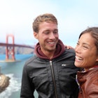 Happy young couple laughing in San Francisco by Golden Gate Bridge. Interracial young modern couple, Asian woman, Caucasian man. 