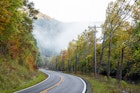 Foggy mist misty scenic highway in rural countryside West Virginia in fog fall autumn season with sunrise by winding road at Monongahela National Forest Appalachian mountains.