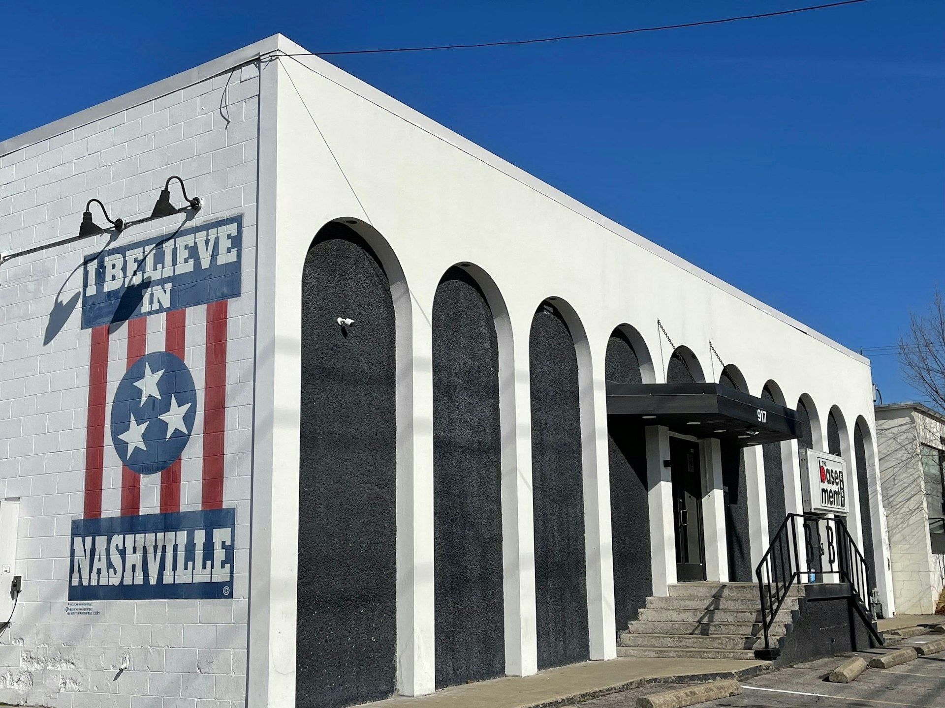 White facade of music venue with red, white and blue "I believe in Nashville" mural painted on the side.
