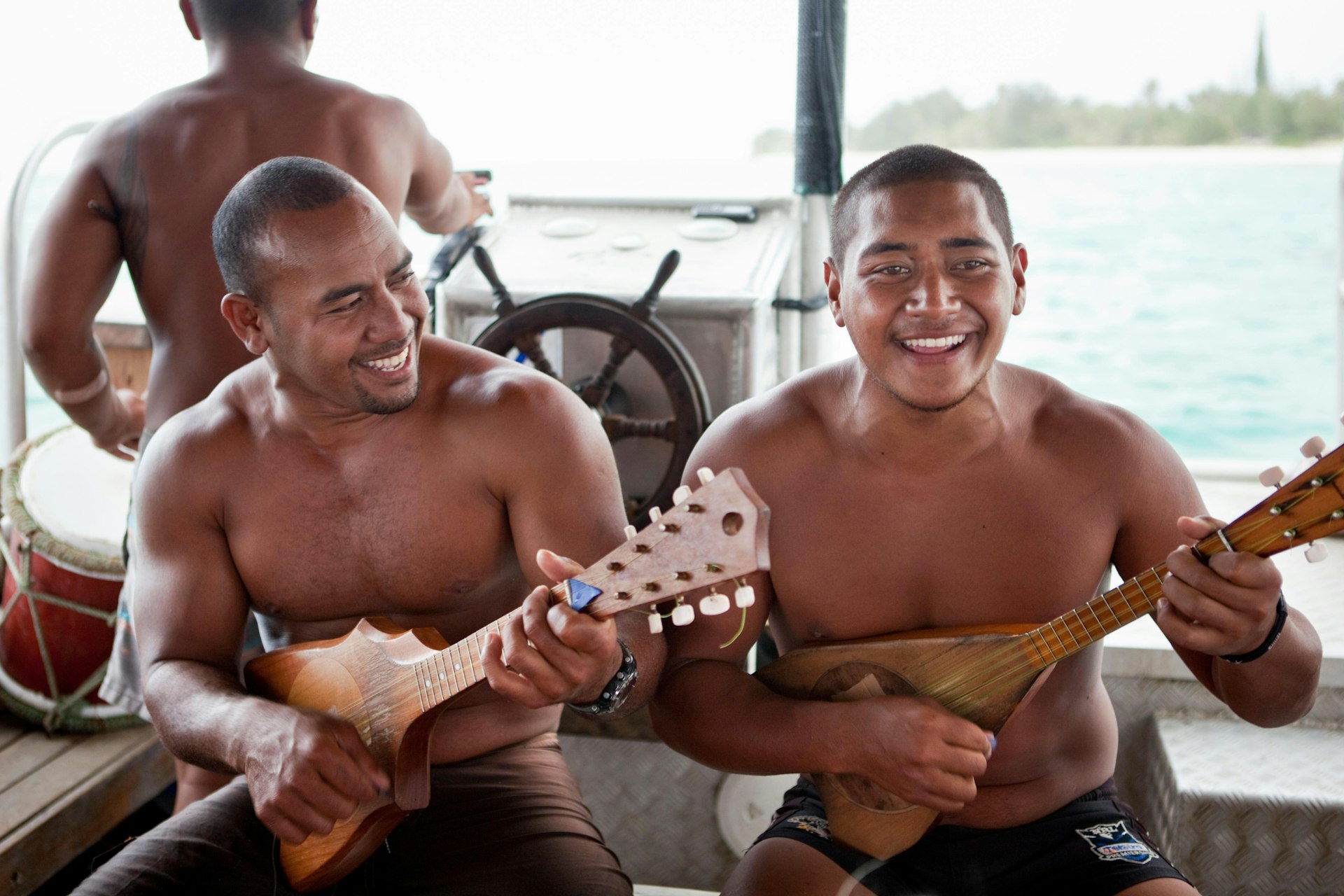 Guides playing ukuleles aboard a glass bottom boat in Muri Lagoon, Rarotonga, Cook Islands.