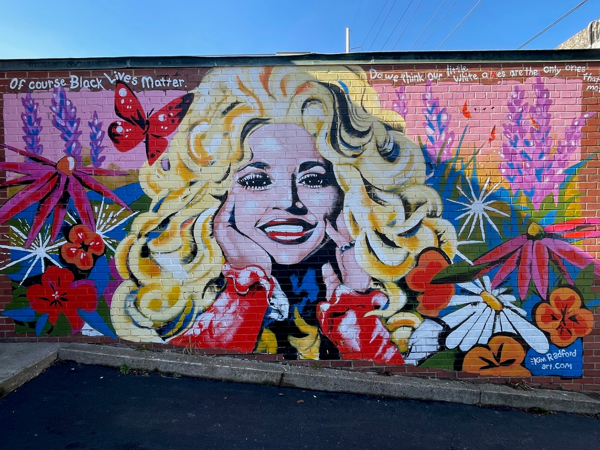 Large mural of country legend Dolly Parton surrounded by pink and purple flowers