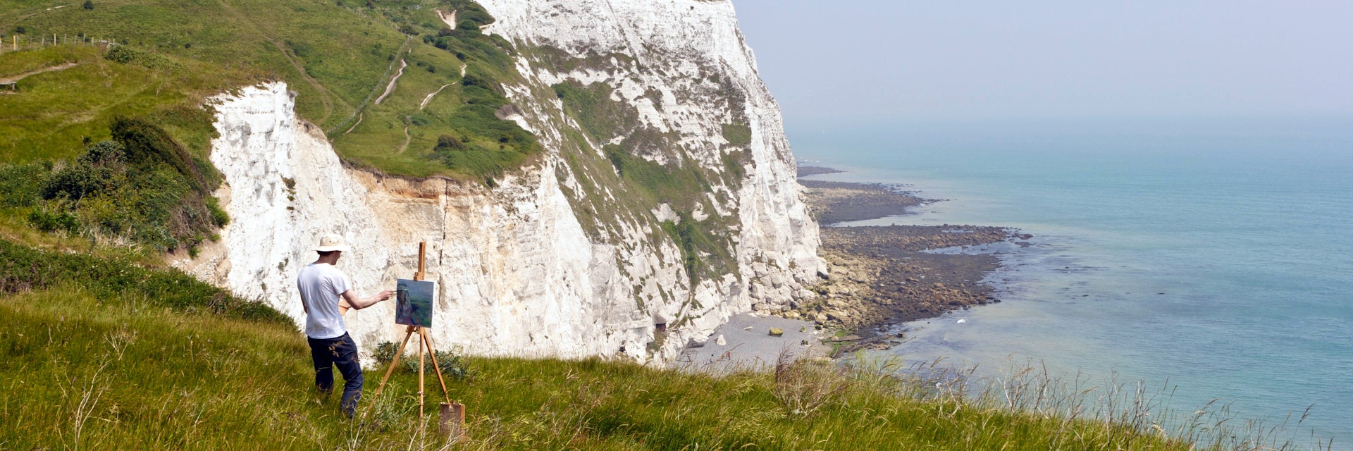 An artist painting the coastline of the Dover Cliffs from the top of the chalky hill, Dover, United Kingdom.