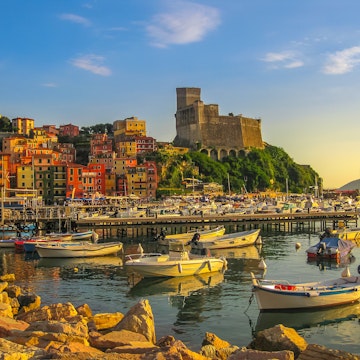 San Giorgio castle above Lerici town from the of Gulf of Poets with sailing boats and motor boats at sunset.