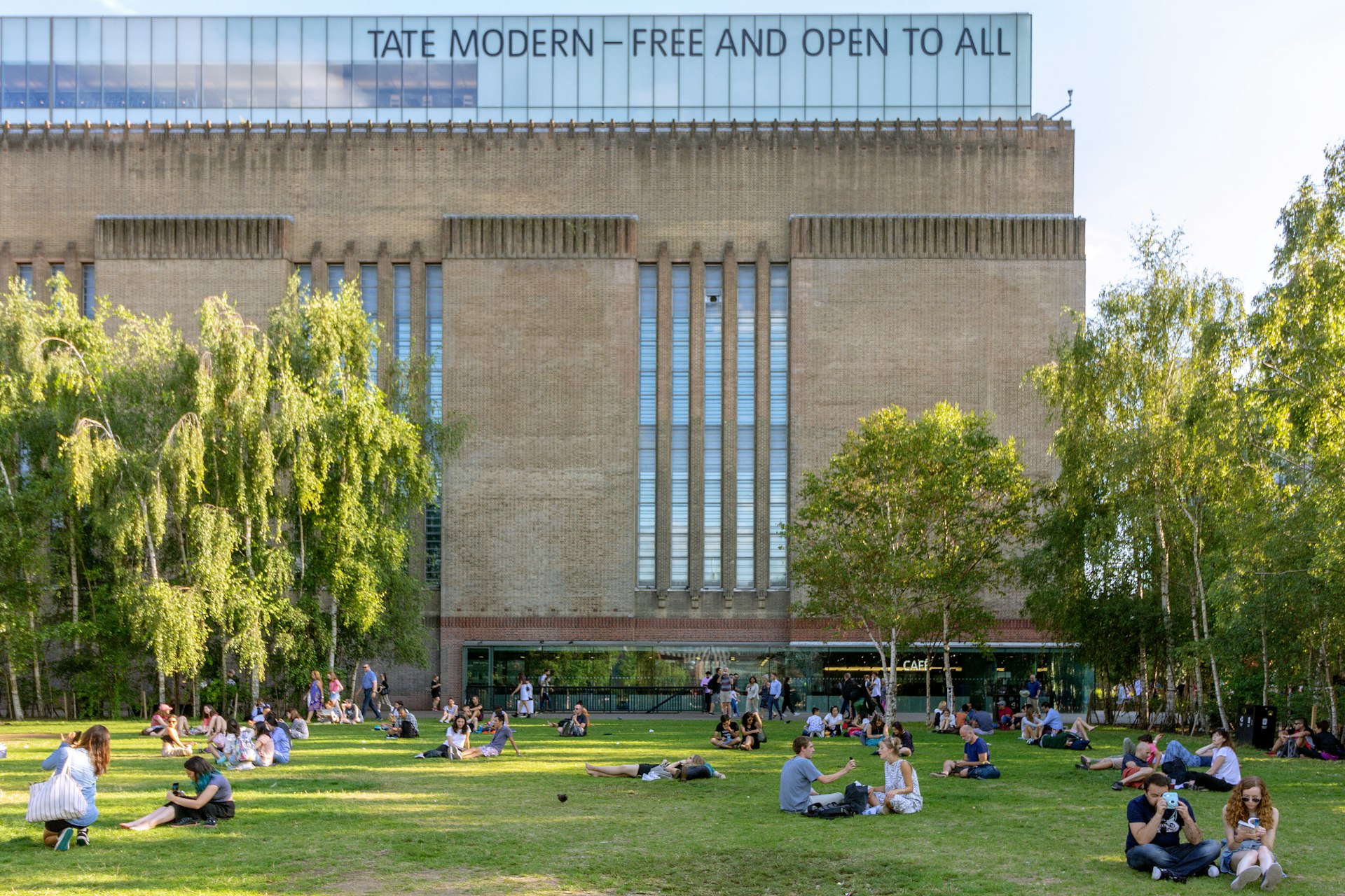 People seated on the grass outside the Tate Modern art gallery. 